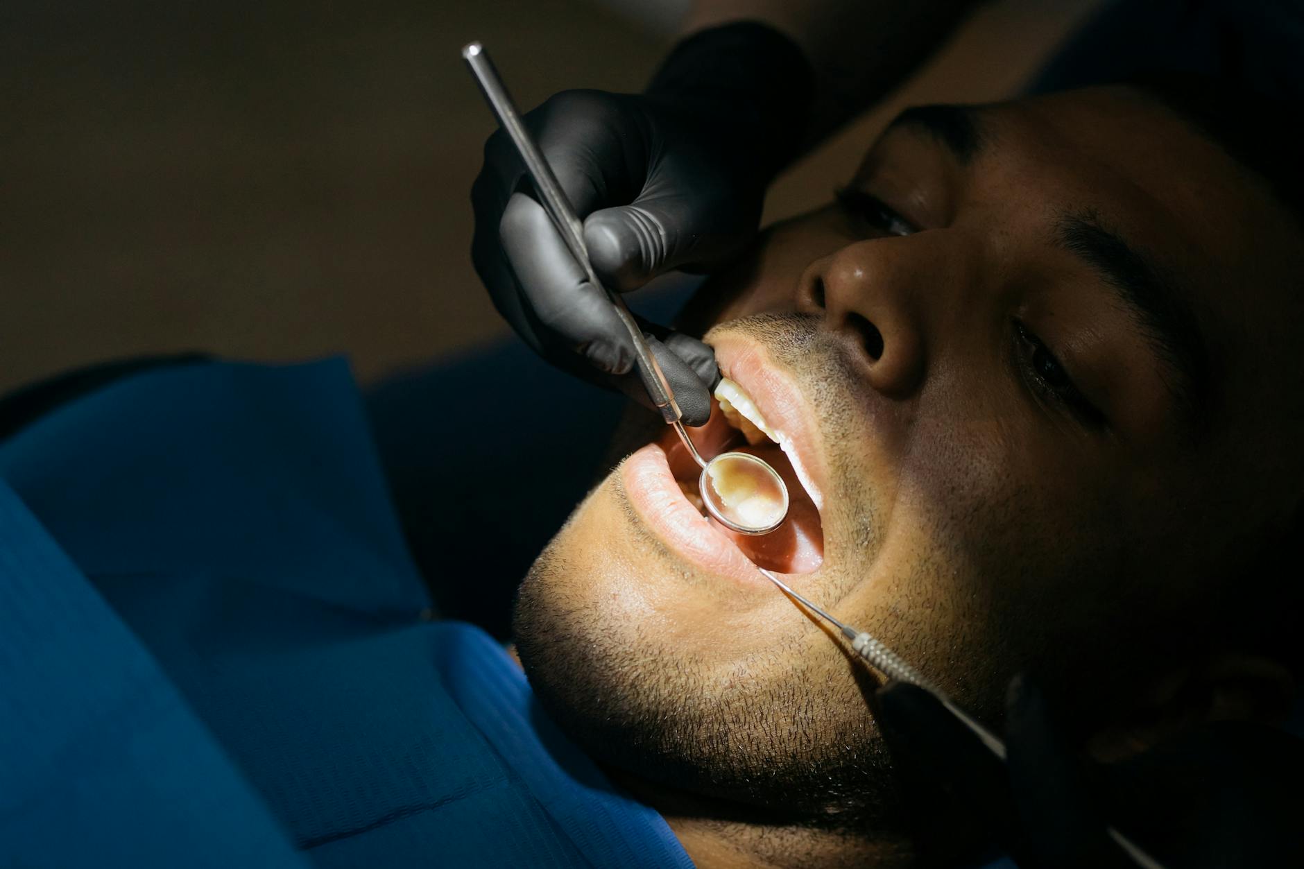 Dentist examining a patient's teeth in a clinic setting.
