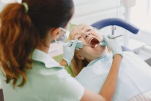 A dentist holding a knocked-out tooth with tweezers, ready to store it in milk.
